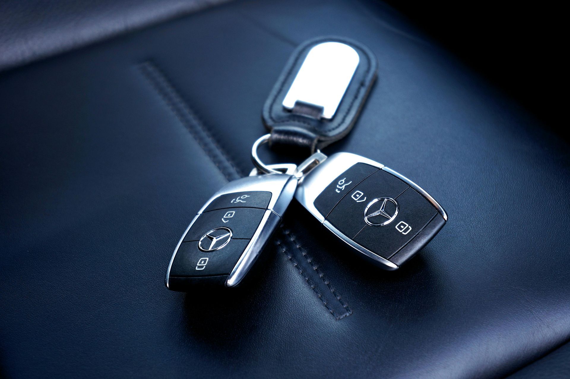 Three car key fobs on a dark leather seat with cool blue lighting