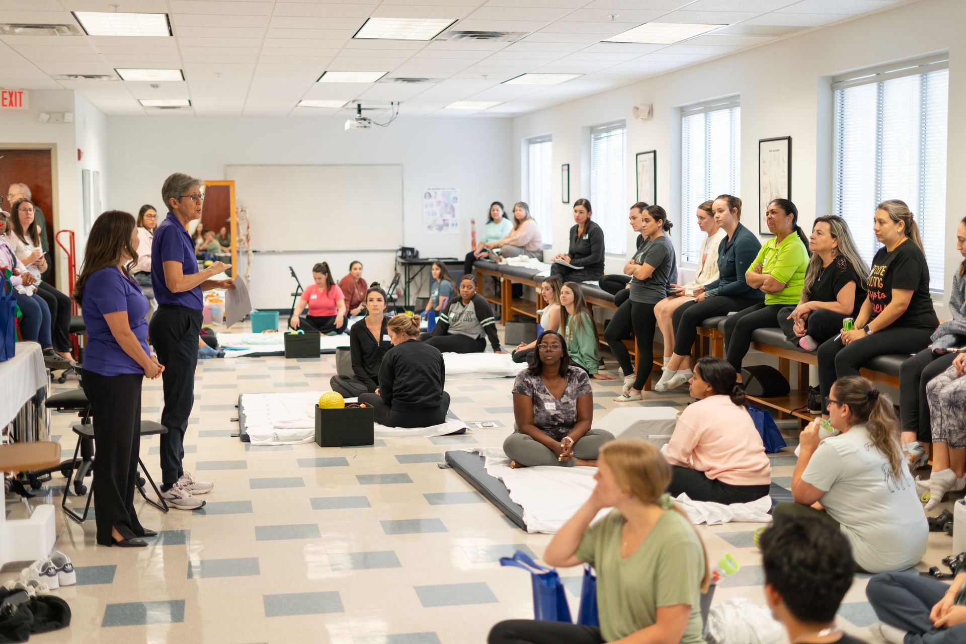 Teacher smiles at students coloring at a table in a classroom.