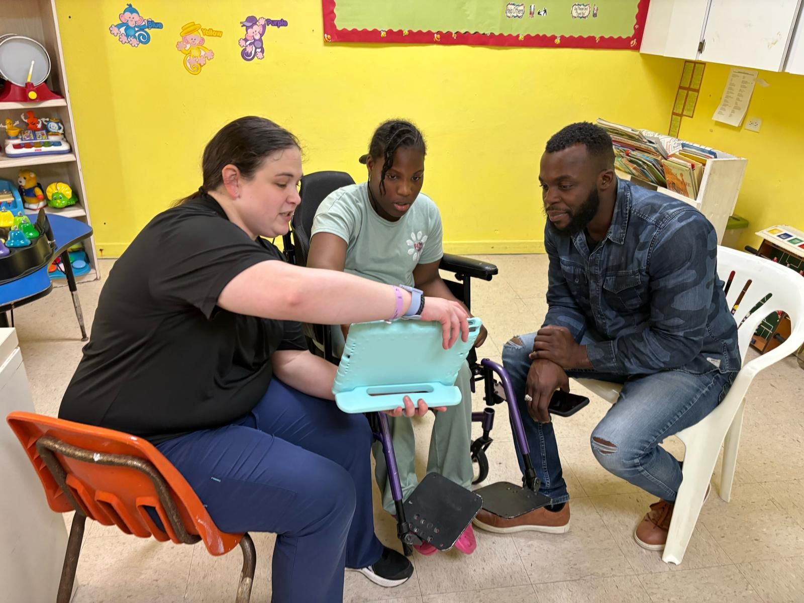 A group of people are sitting around a child in a wheelchair.