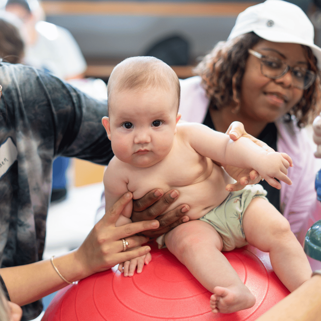 A baby is sitting on a red exercise ball