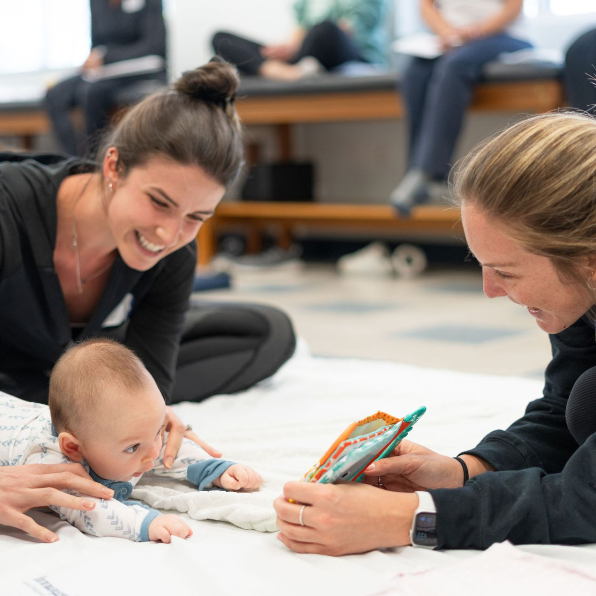 Two women are playing with a baby on the floor