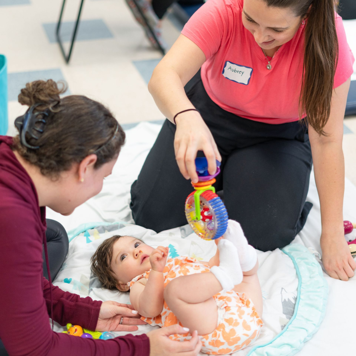 Two women are playing with a baby who is wearing a diaper