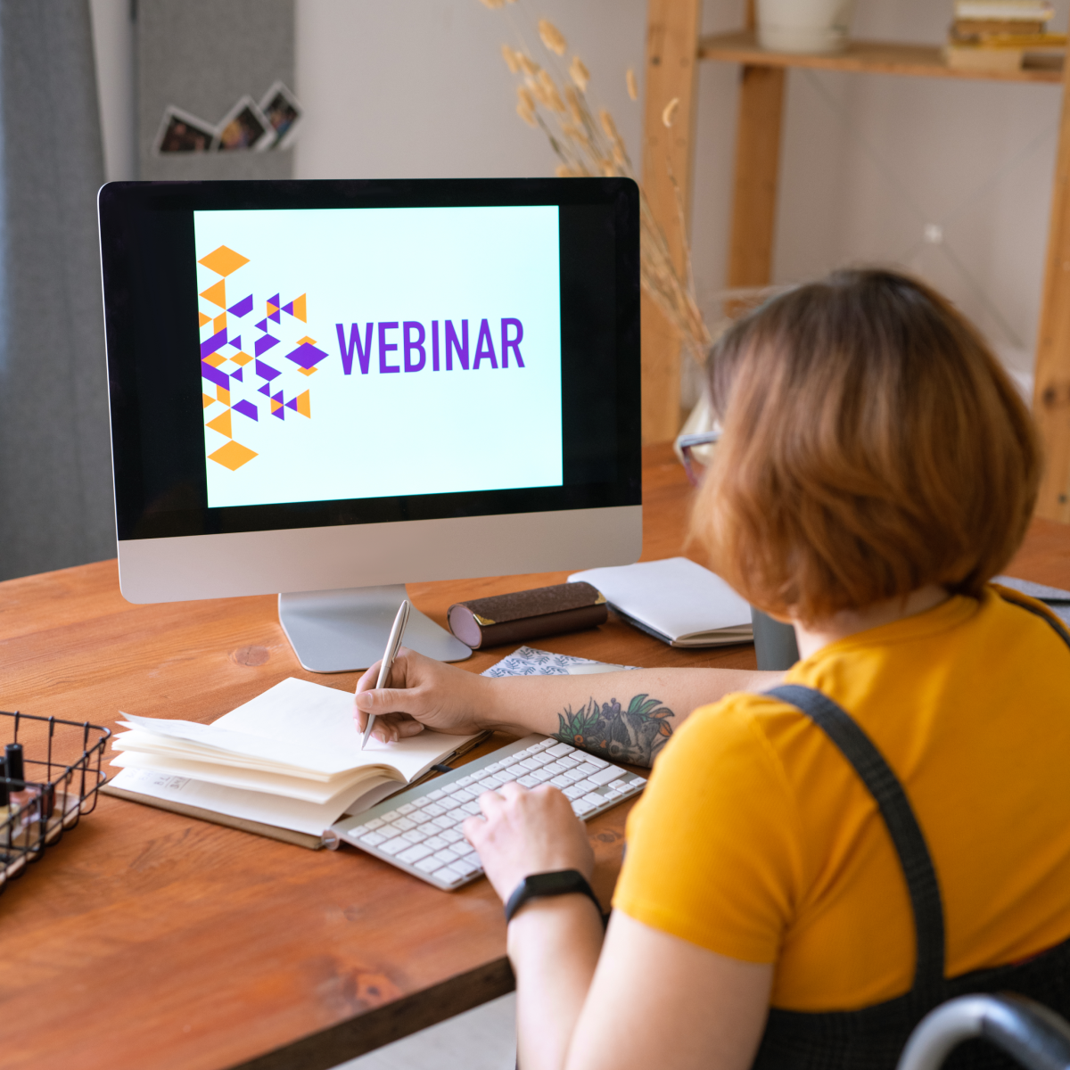 A woman is sitting at a desk with a computer that says webinar on the screen