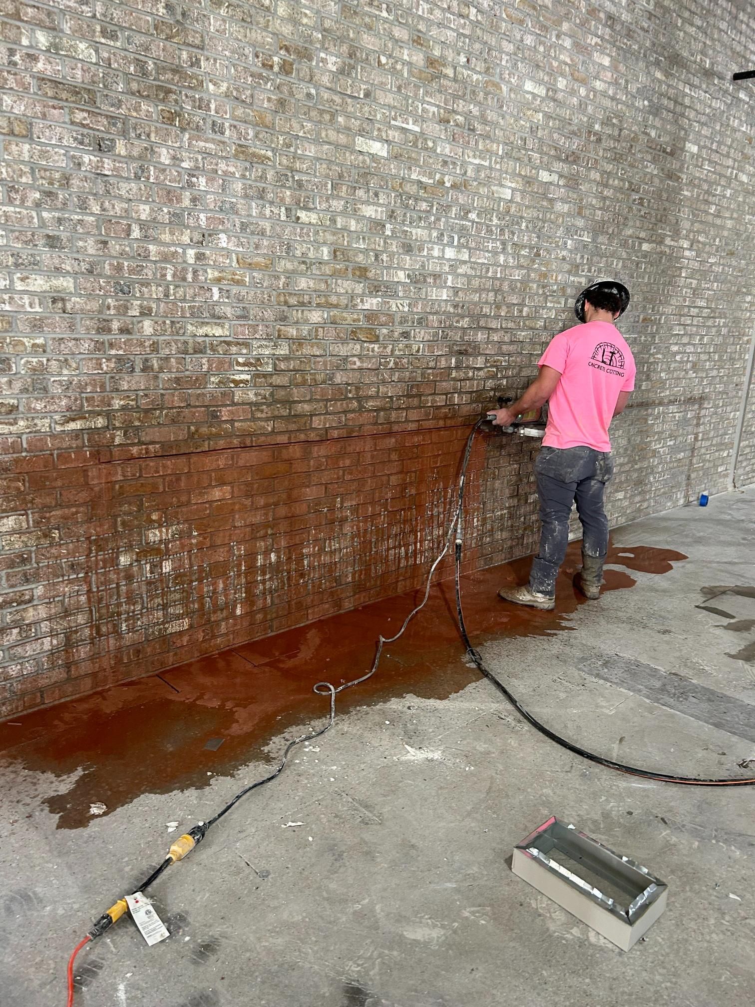 A man is cleaning a brick wall with a hose.