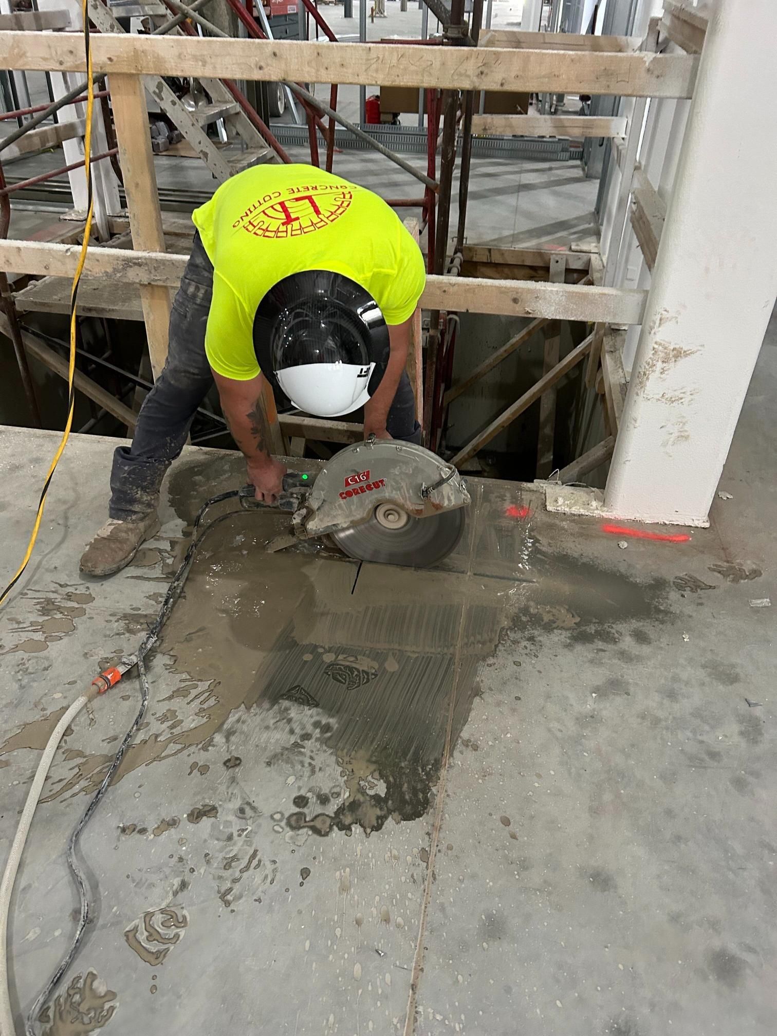 A construction worker is cutting concrete with a circular saw.