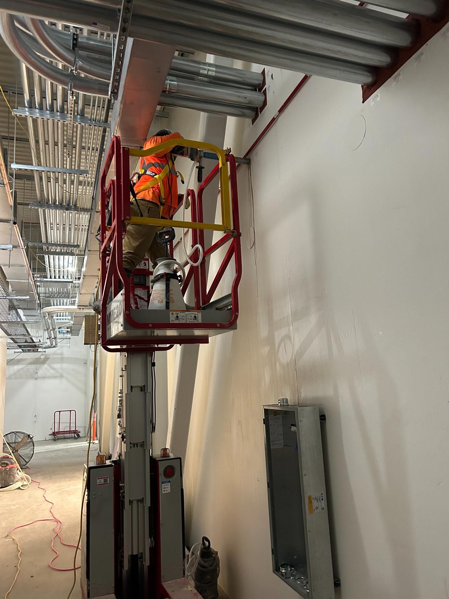A man is standing on a lift working on a wall.