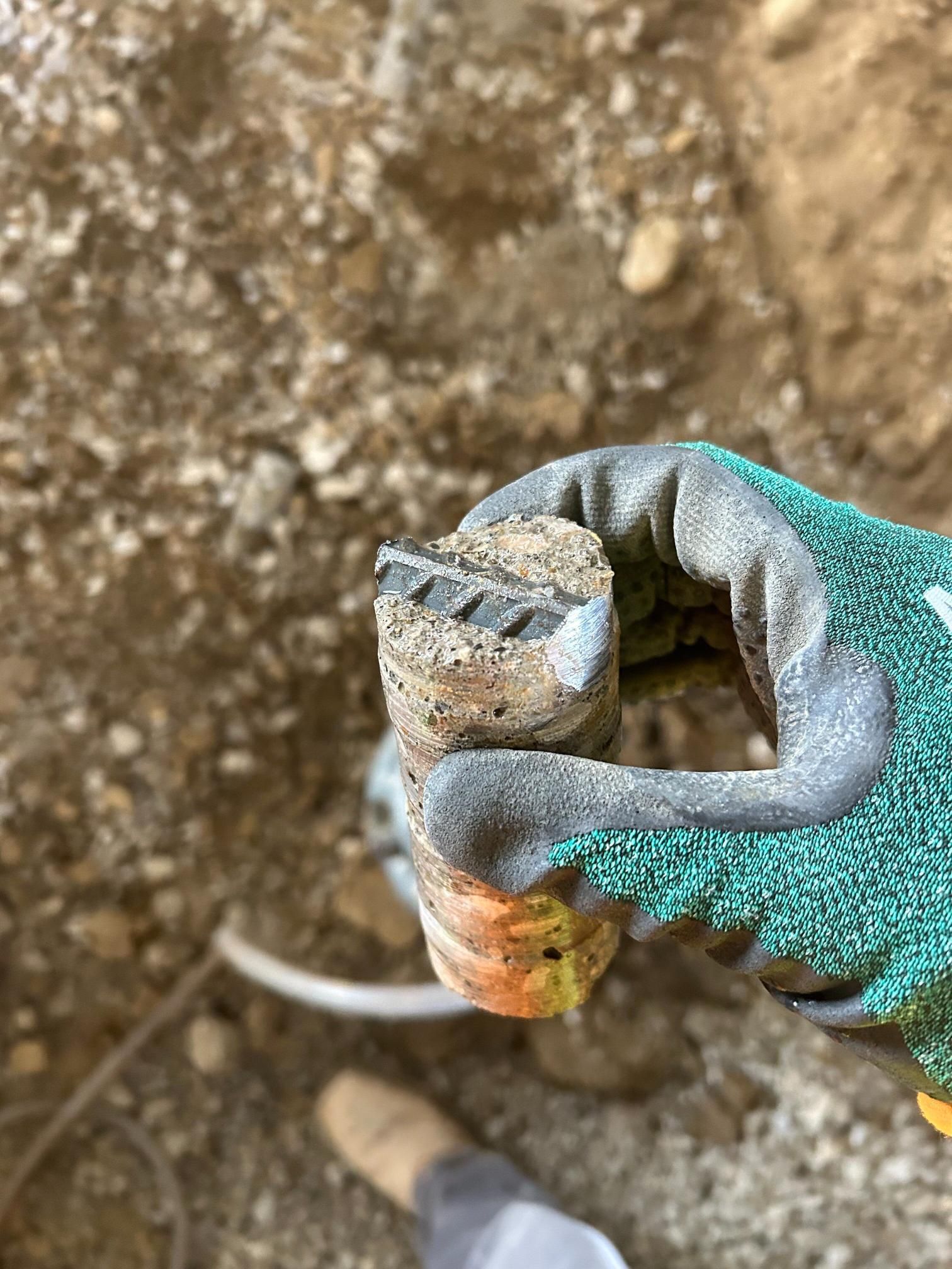 A person wearing a glove is holding a piece of rock in their hand.