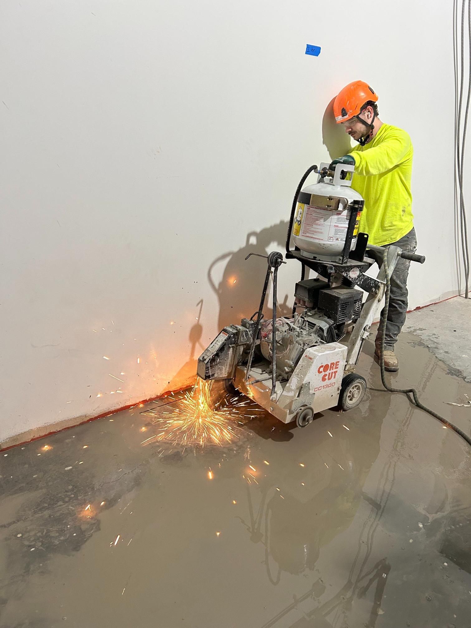 A man is using a machine to cut a hole in a wall.