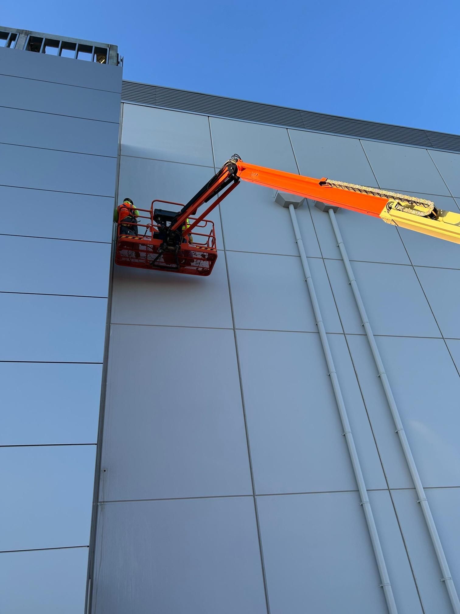 A crane is being used to paint the side of a building