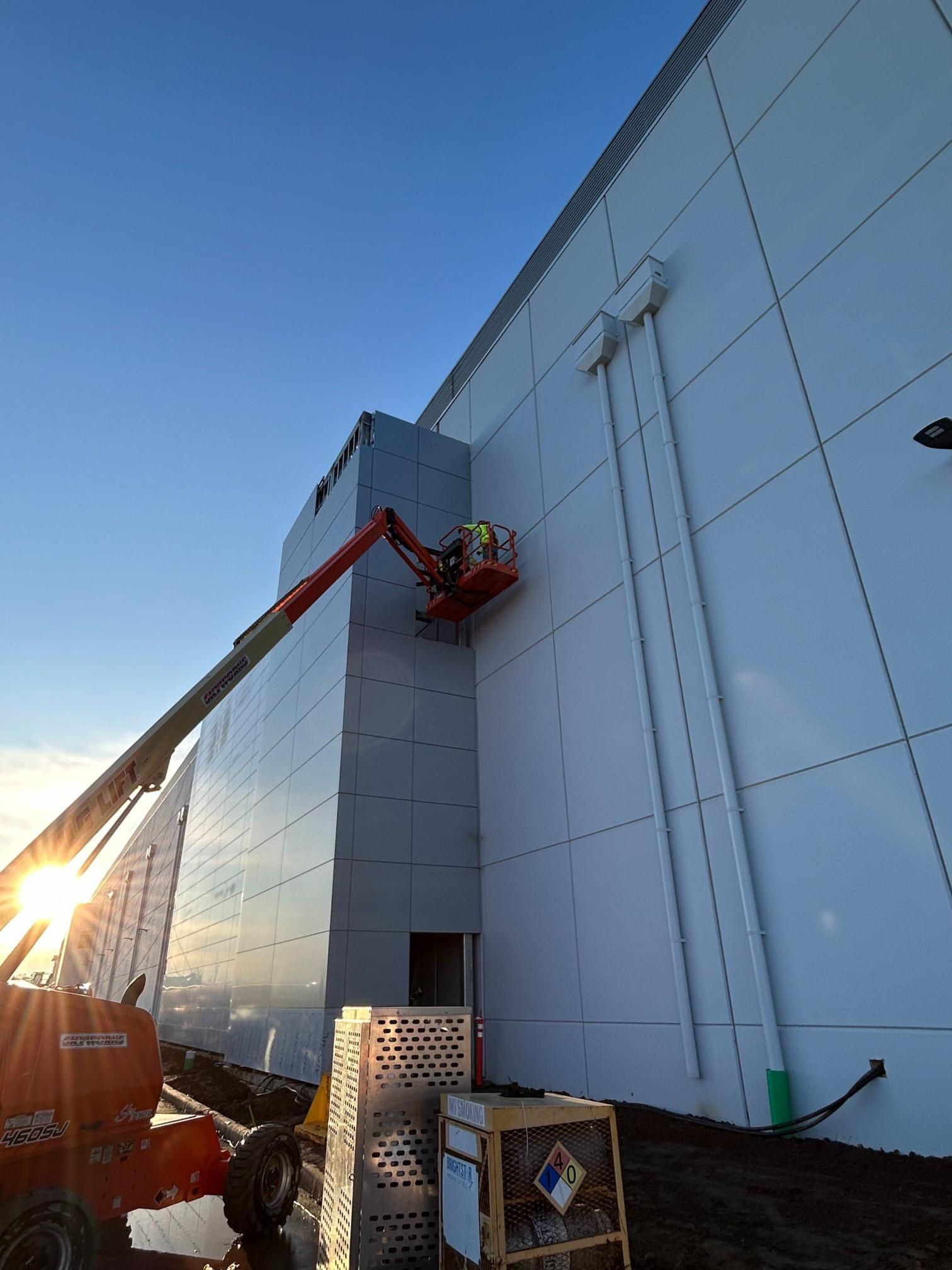 A man is painting the side of a building with a crane.