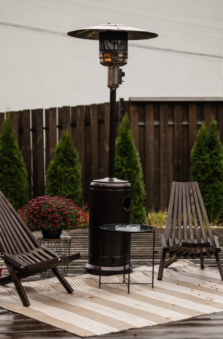 A patio with chairs and a heater on a rug.