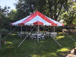 A red and white tent with tables and chairs underneath it