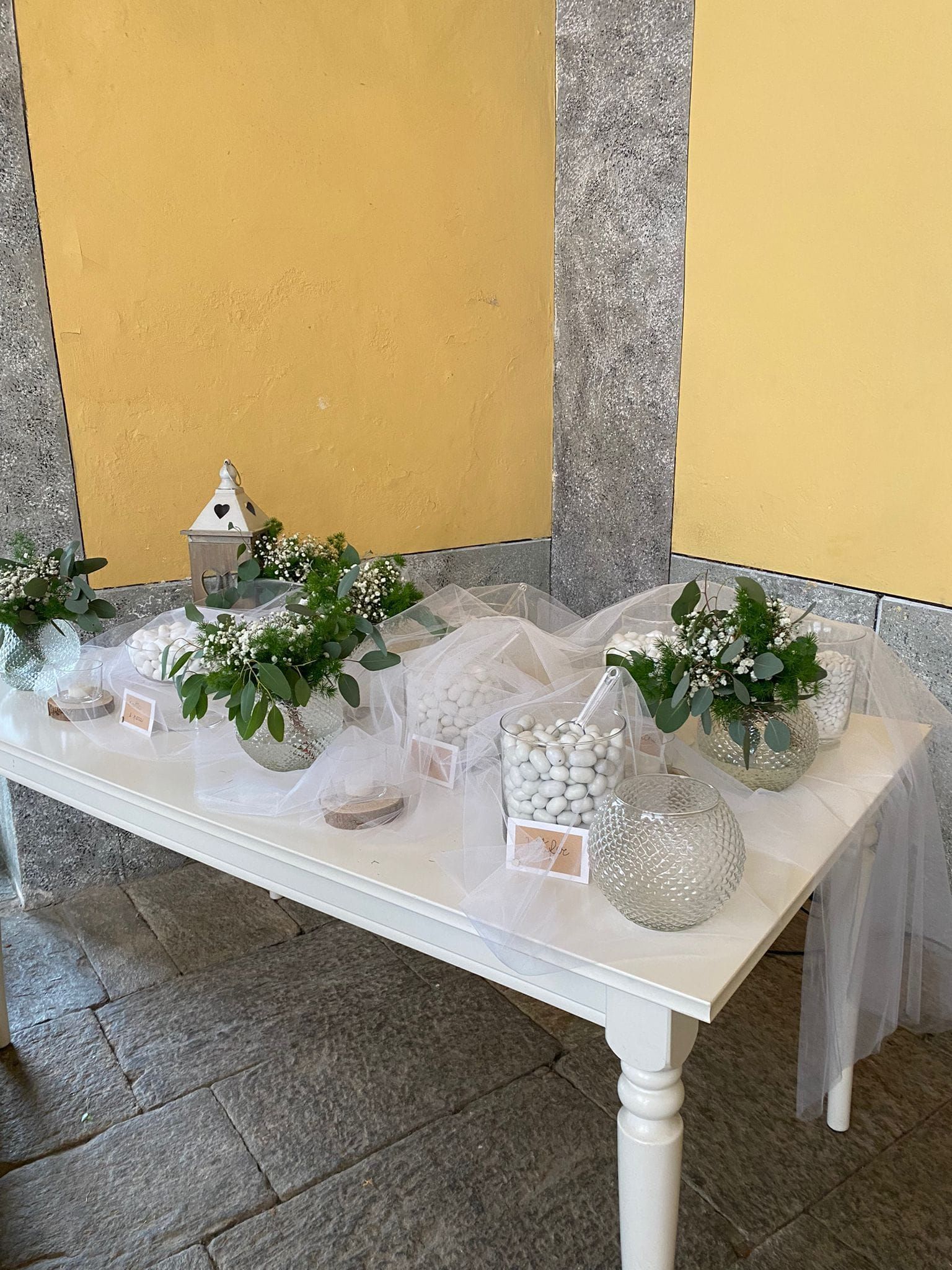 Un tavolo bianco con fiori e dolciumi sopra.