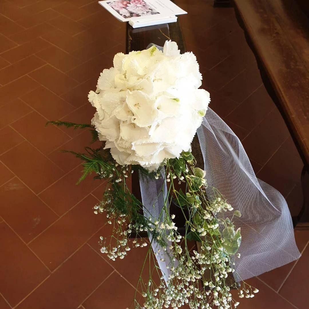 Un mazzo di fiori bianchi è appoggiato su una panca di legno