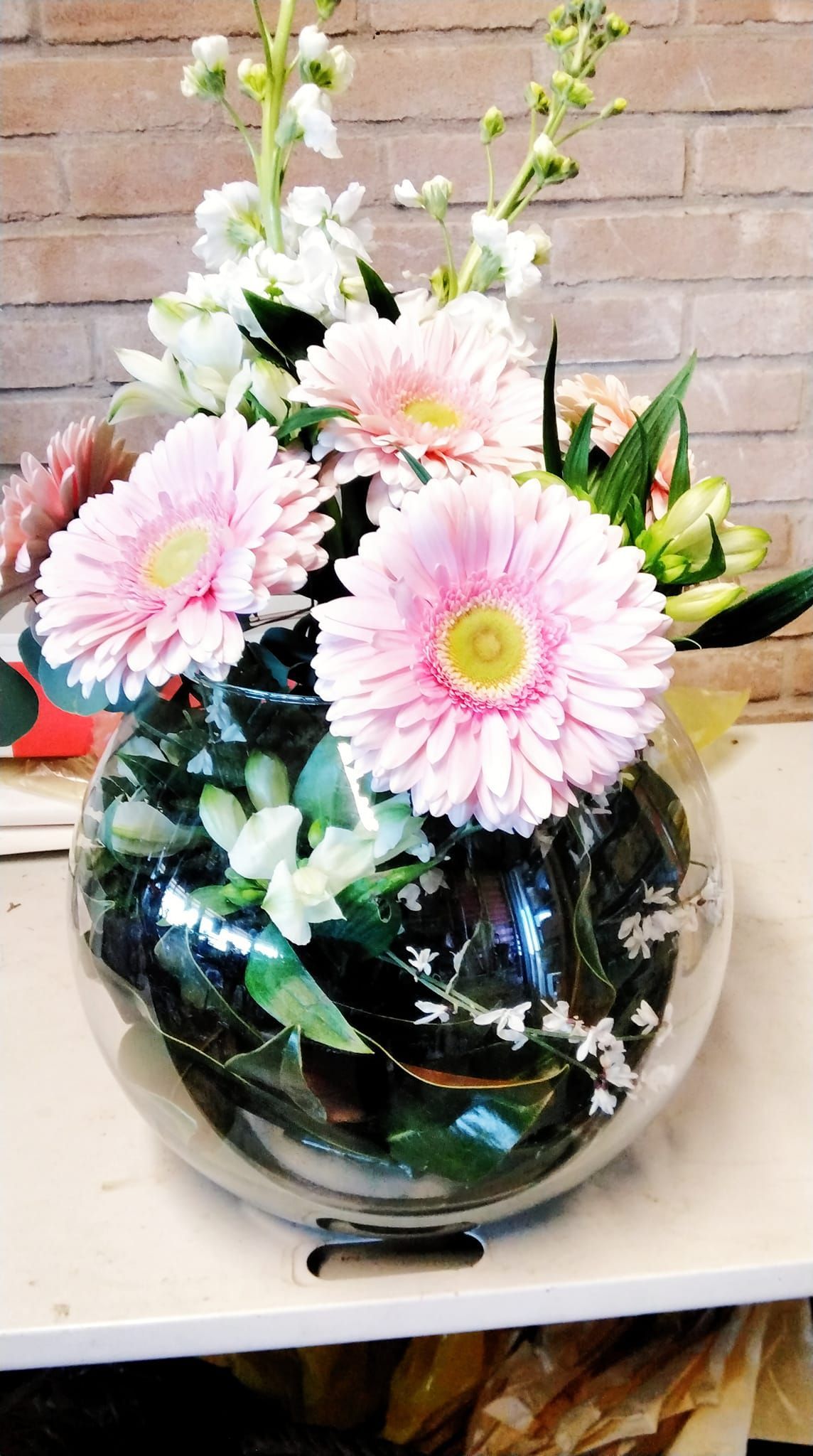 Una ciotola di vetro piena di margherite rosa e fiori bianchi