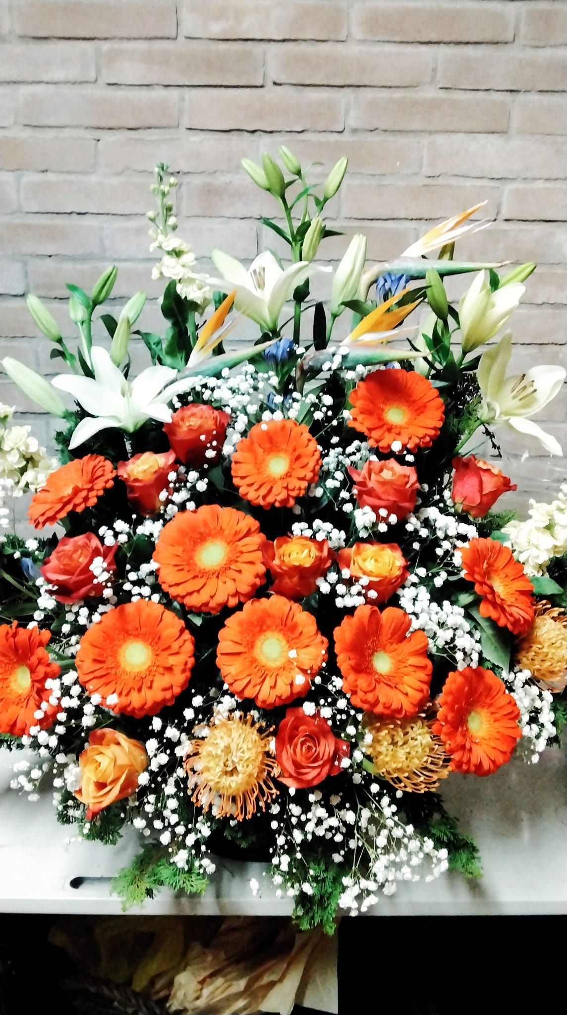 Un grande mazzo di fiori arancioni e bianchi contro un muro di mattoni