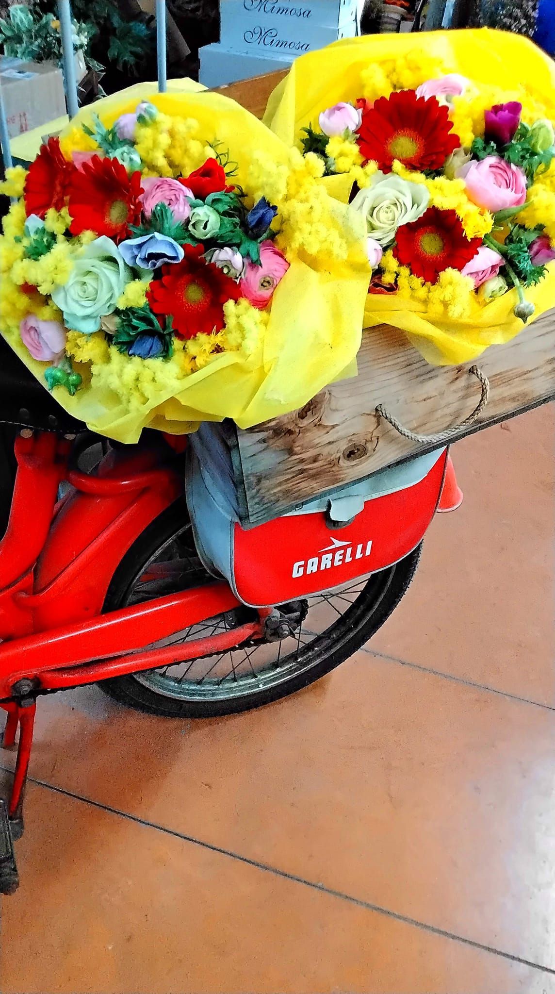 Due mazzi di fiori sono sul retro di una motocicletta rossa