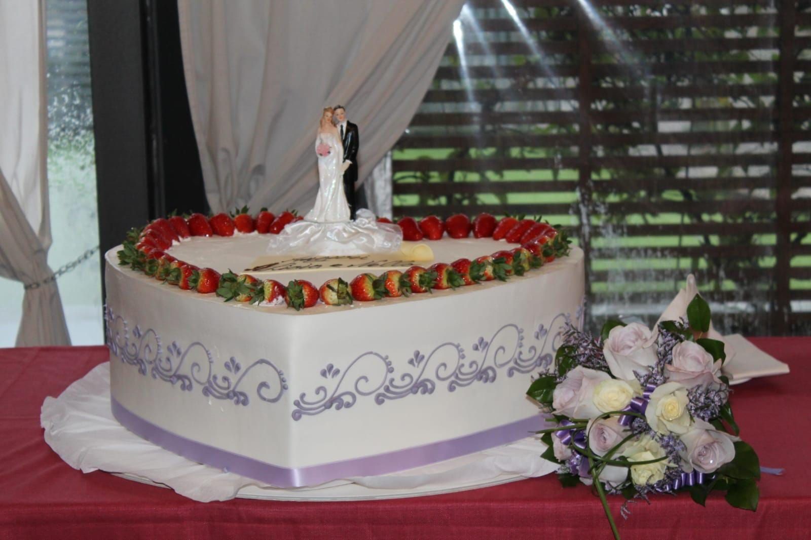 Una torta nuziale a forma di cuore con una statuina degli sposi in cima