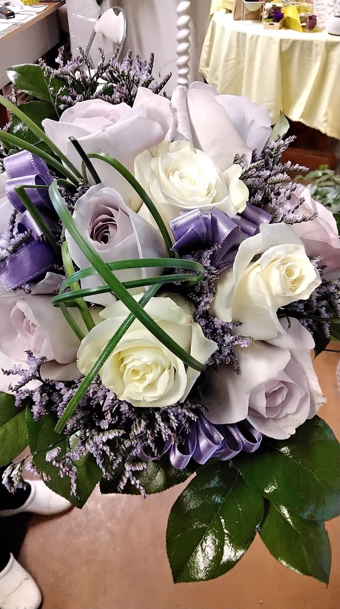 Un mazzo di fiori viola e bianchi è appoggiato su un tavolo.