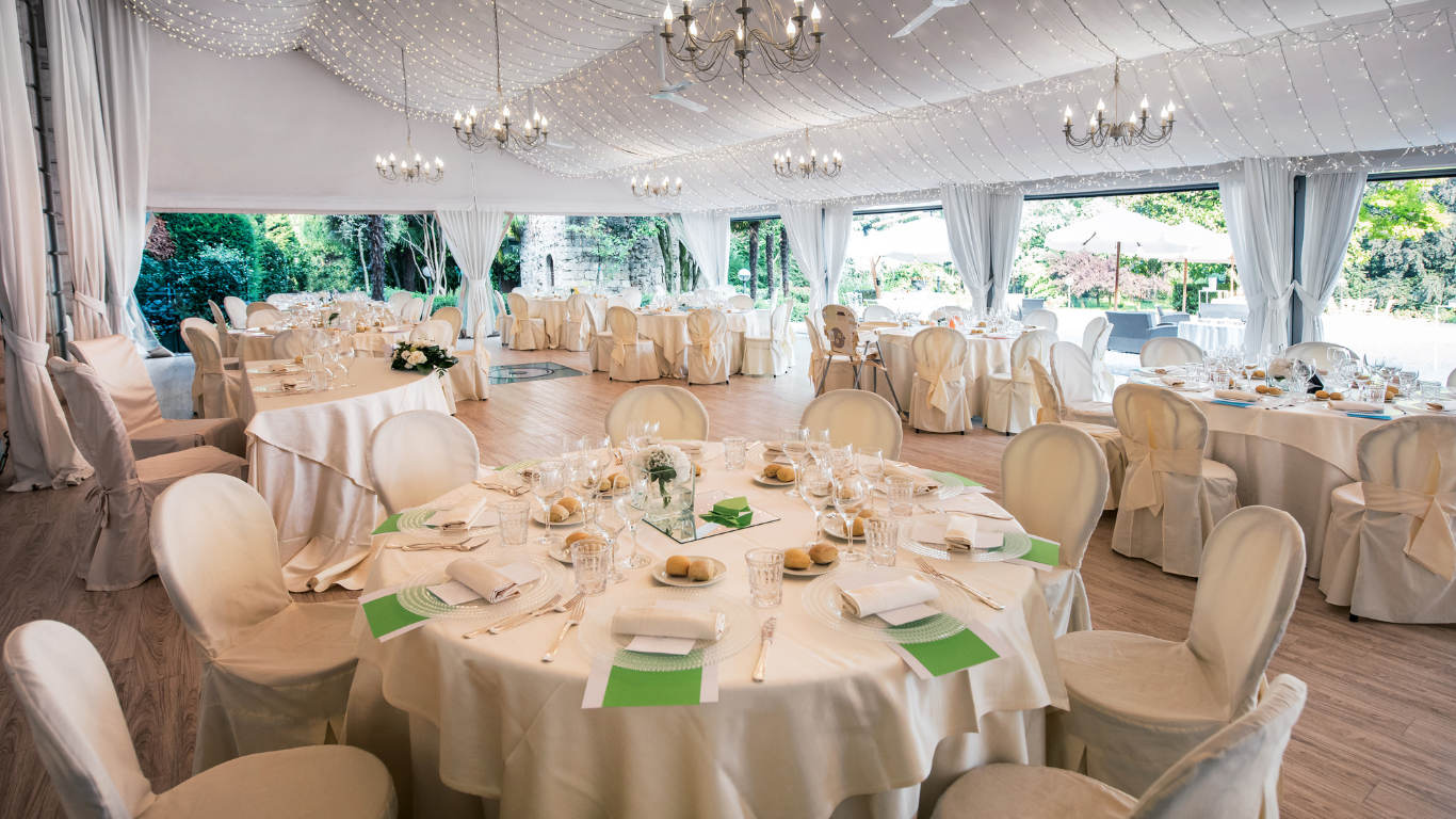 A large room with tables and chairs set up for a wedding reception.