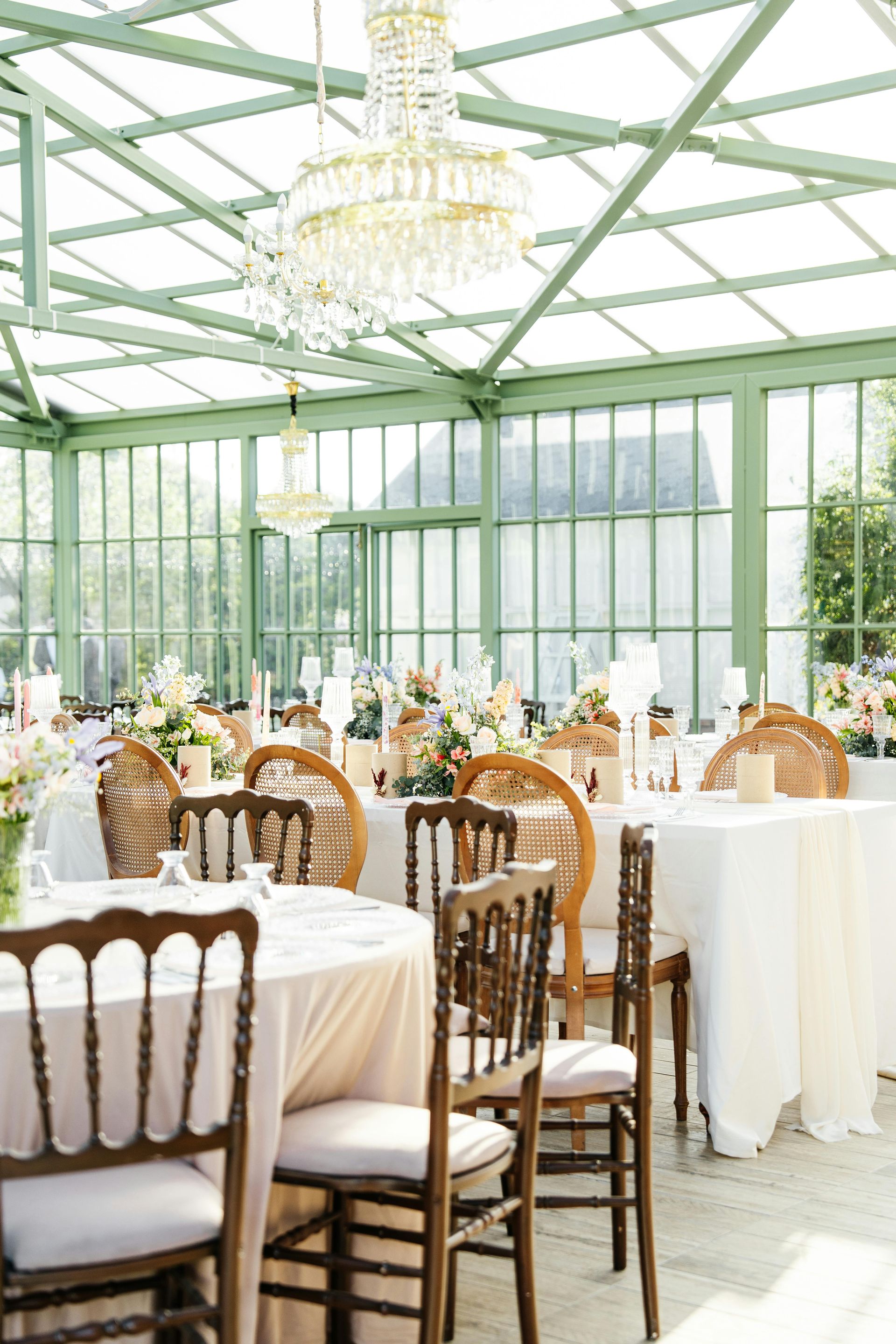 A greenhouse with tables and chairs set up for a wedding reception