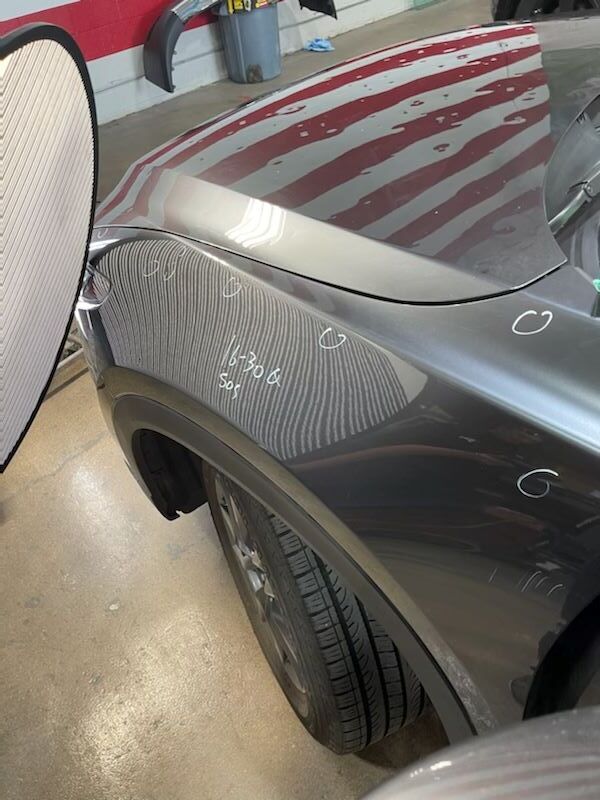 A car is parked in a garage with a red white and blue striped floor.