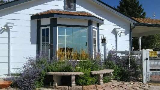 A white house with a bay window and a bench in front of it