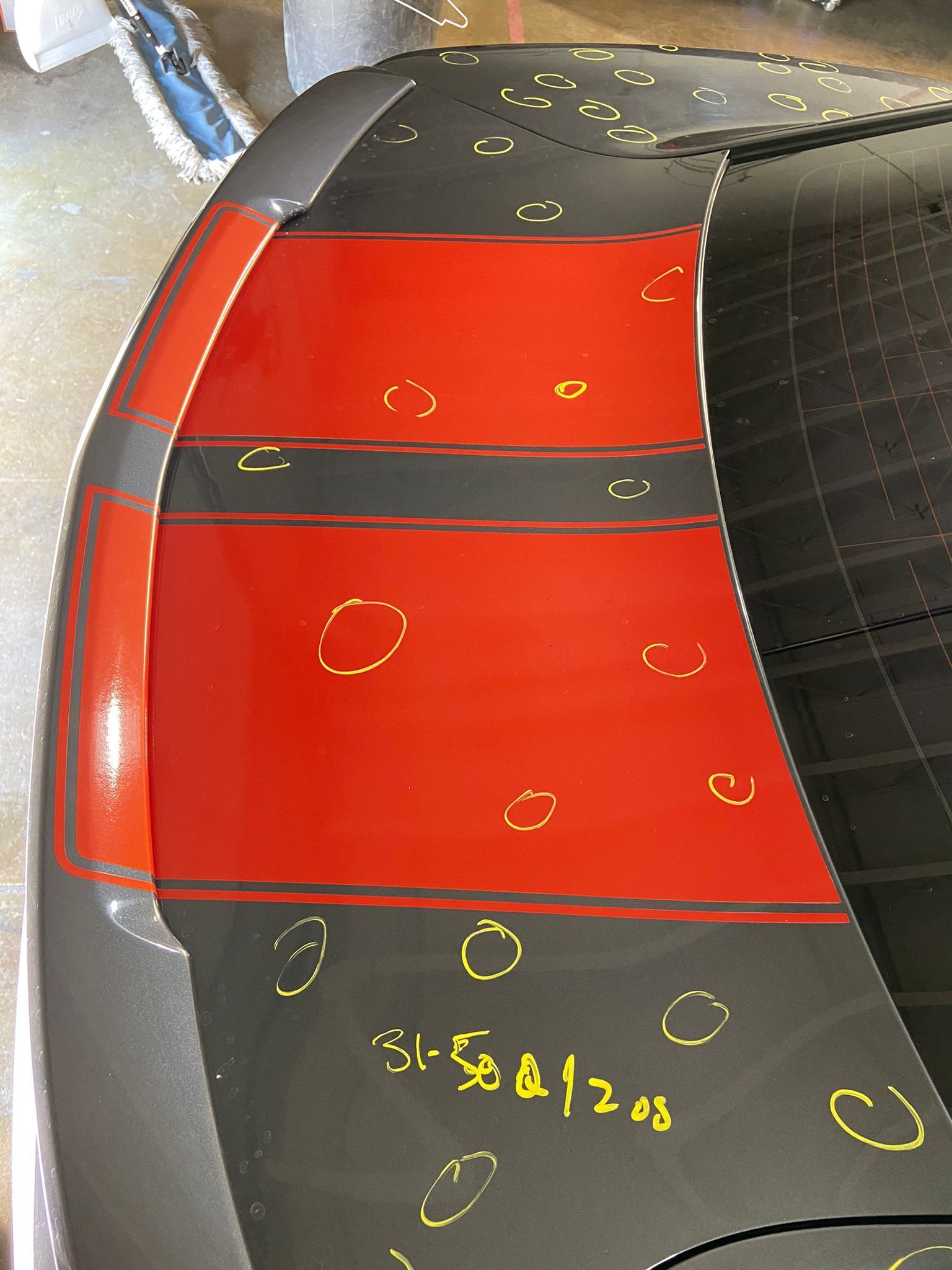 A close up of a red and black car with hail damage