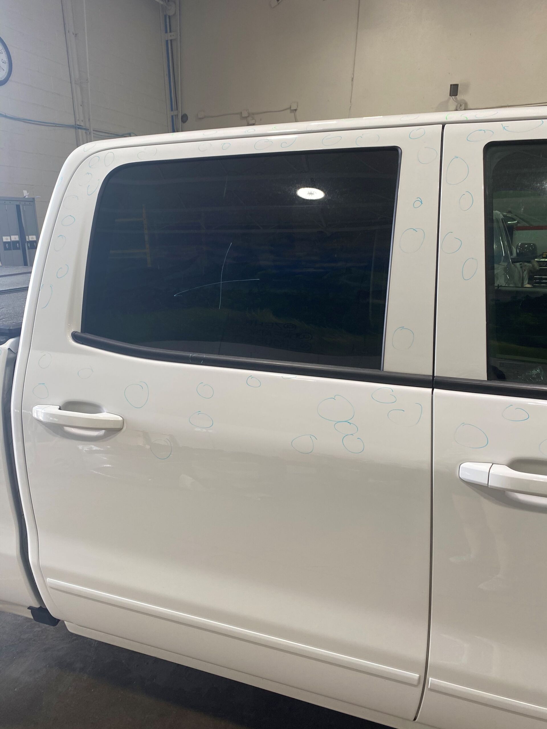 A white truck is parked in a garage with the door open.
