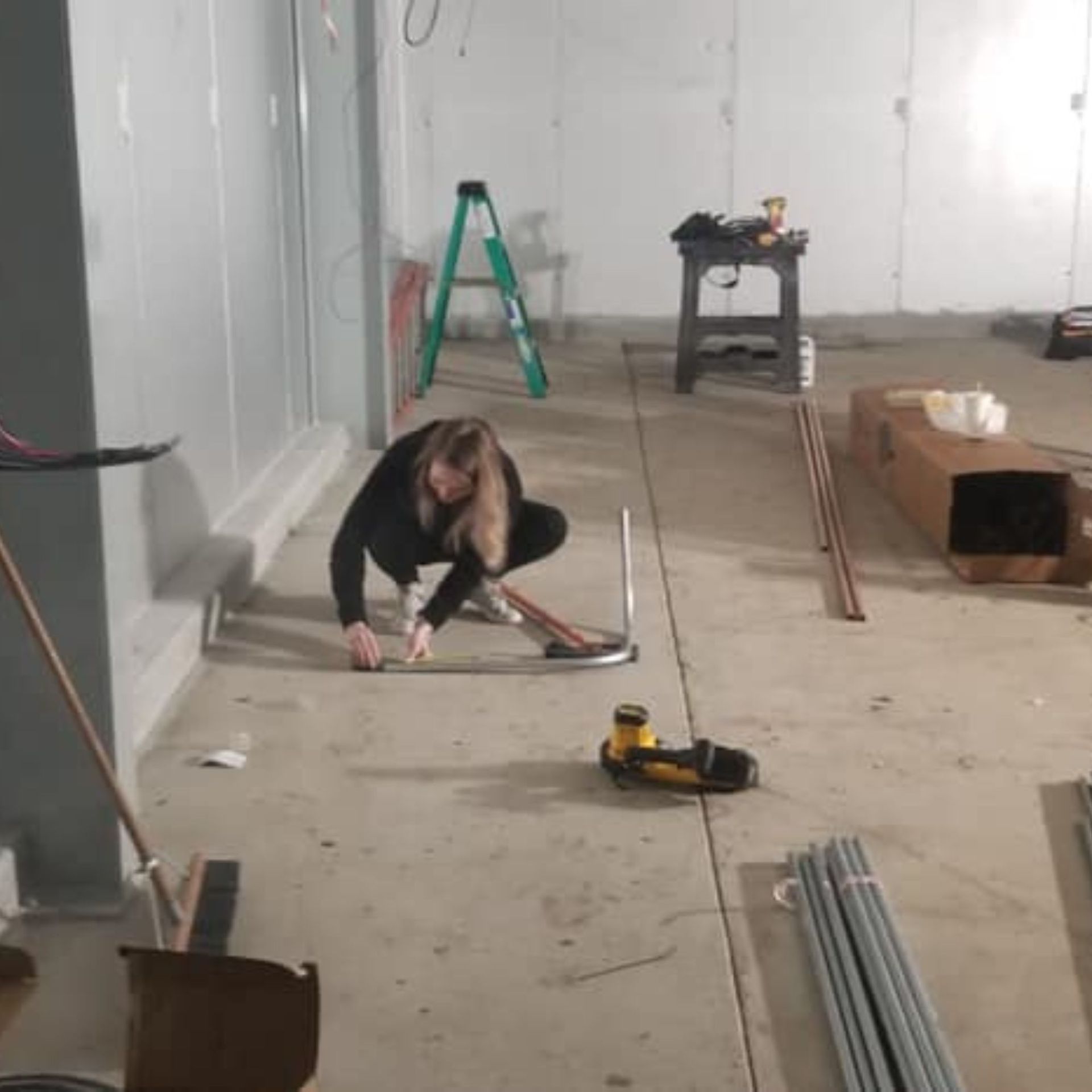 Harrington Electric LLC - A woman is kneeling on the floor measuring a piece of metal.