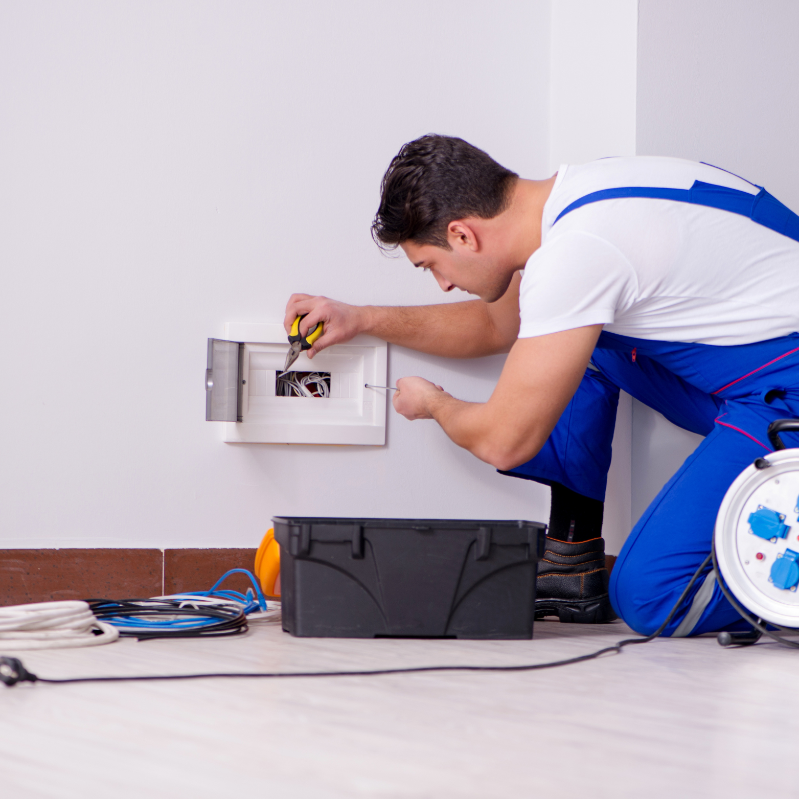 Harrington Electric LLC - A man in blue overalls is working on an electrical box