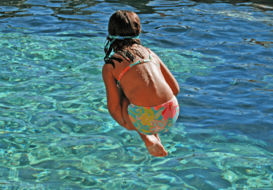 A girl in a bikini is jumping into the water.