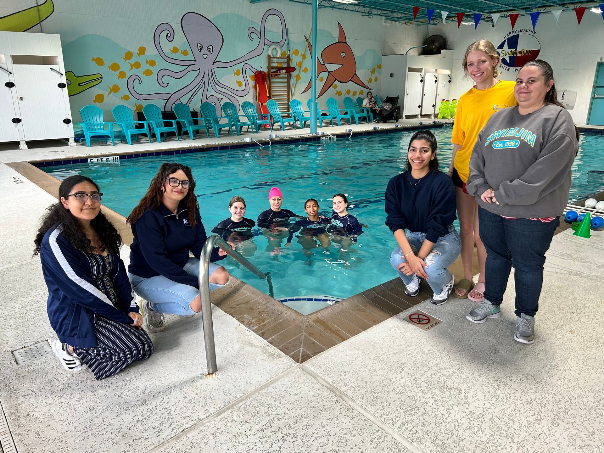 A group of people are posing for a picture in front of a swimming pool.