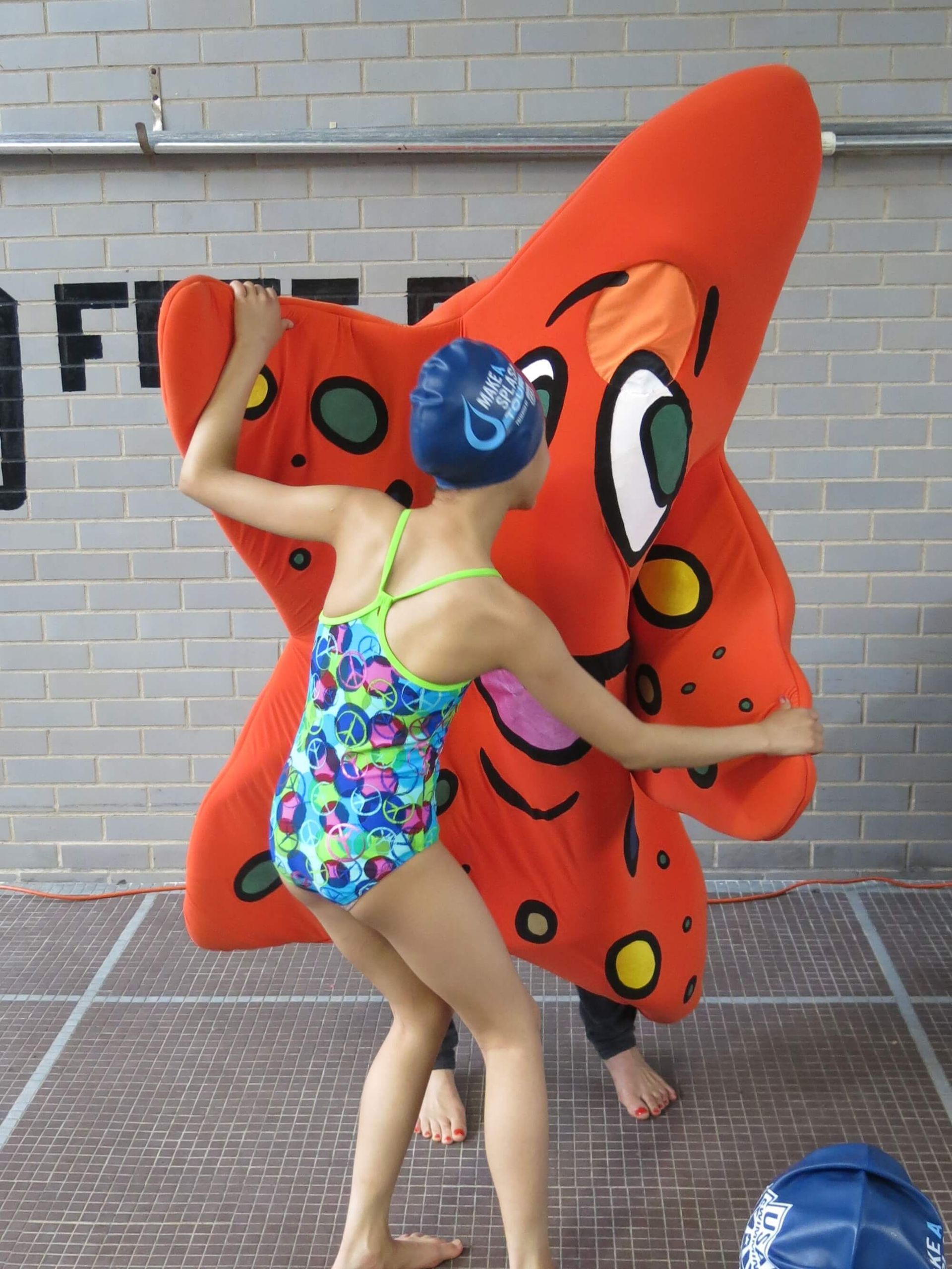 A girl in a swimsuit is holding a stuffed starfish