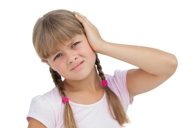 A young girl is holding her ear because she has a headache.