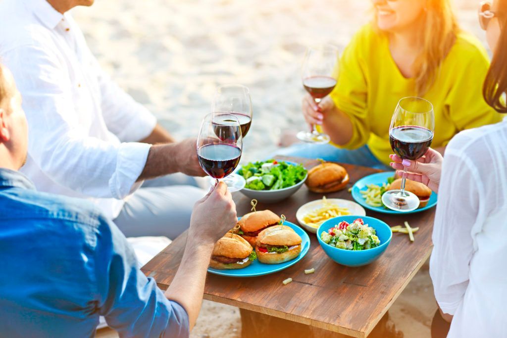 A group of people are sitting around a table eating food and drinking wine.