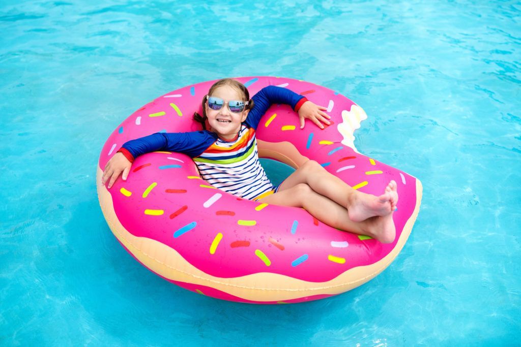 A little girl is floating on an inflatable donut in a swimming pool.