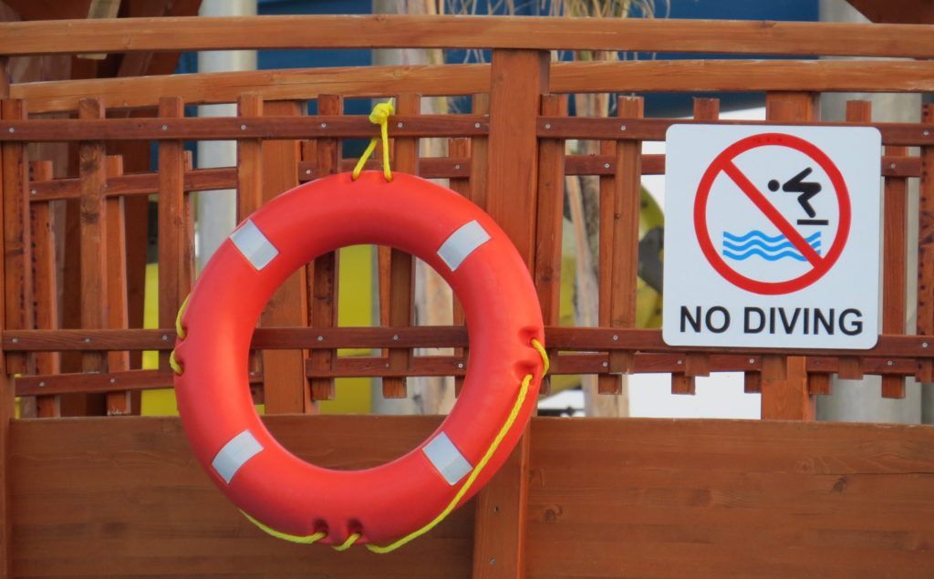 A life preserver is attached to a wooden railing next to a no diving sign