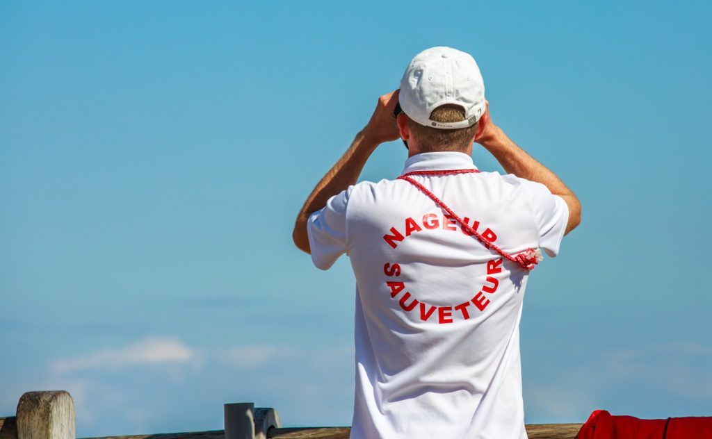 A man in a white shirt and hat is looking at the sky.