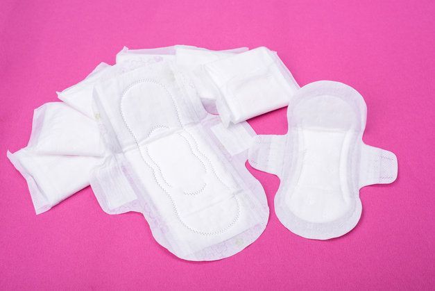 A pile of white sanitary pads on a pink surface.