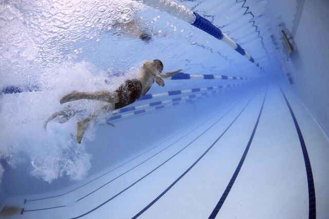 A group of people are swimming in a swimming pool.