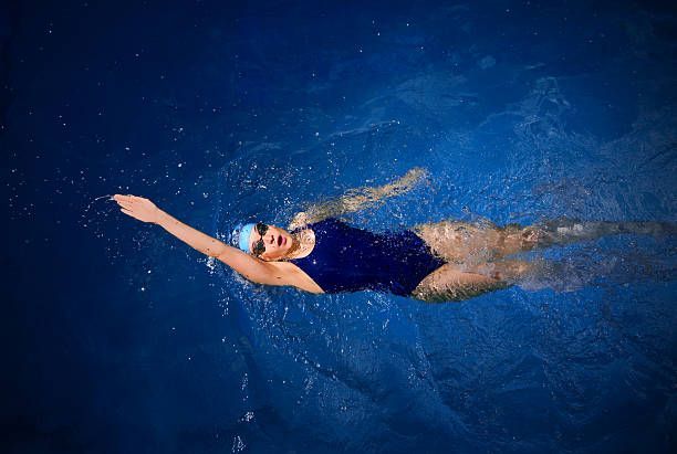 A woman is swimming in a swimming pool.