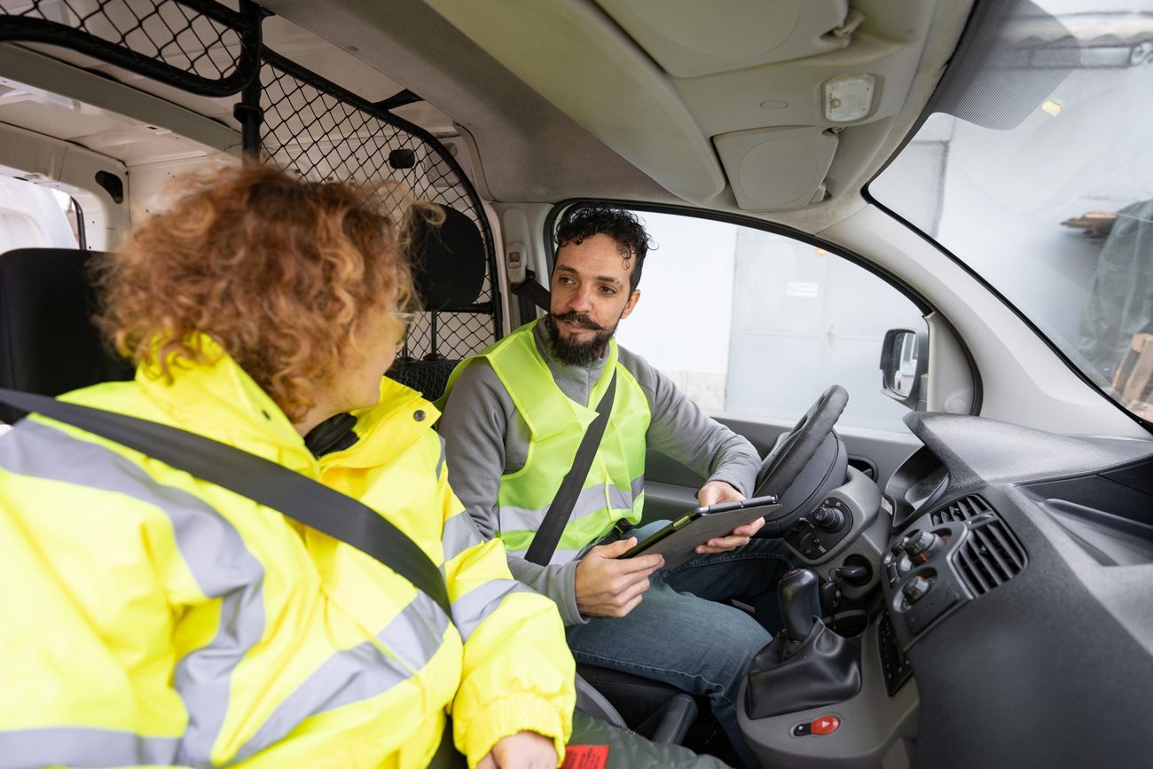 A man and a woman are sitting in a van talking to each other. A man and a woman are sitting in a van talking to each other.