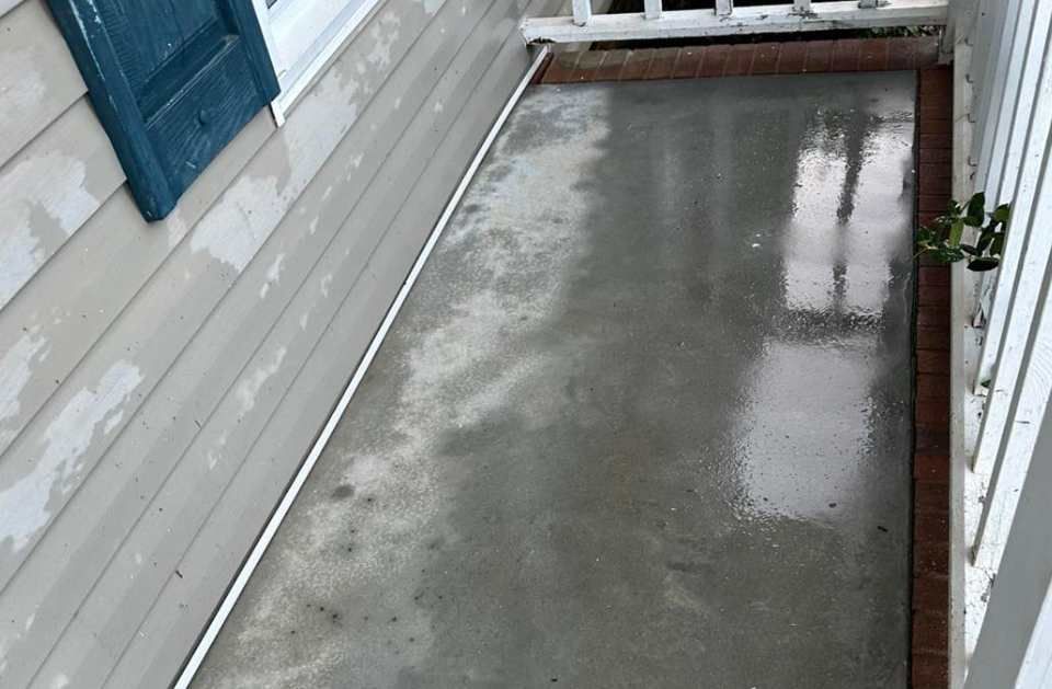 A concrete walkway is being built on the side of a house.