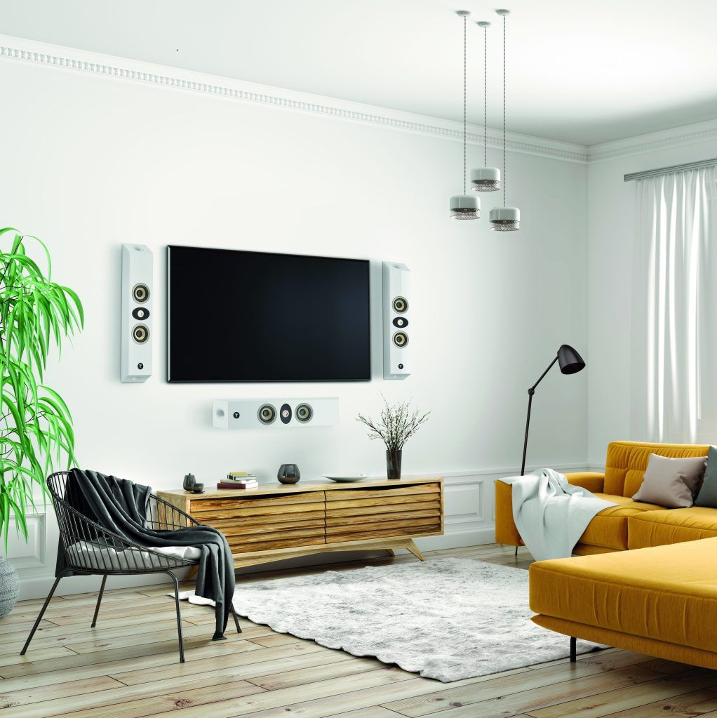 Living room with large TV, yellow couch, speakers, and decor against a white wall.