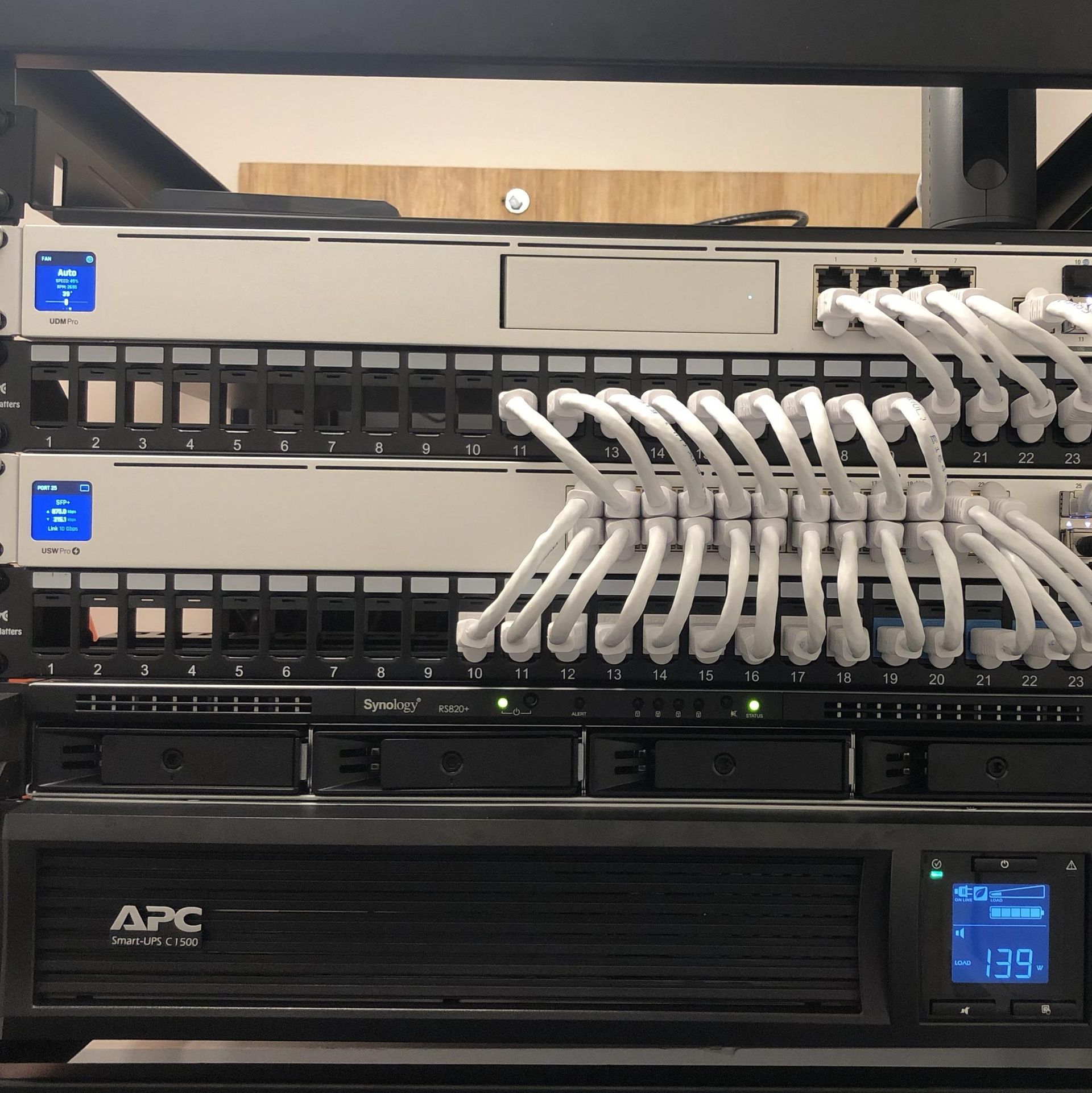 Network server rack with white patch cables, multiple switches, and an APC UPS unit.