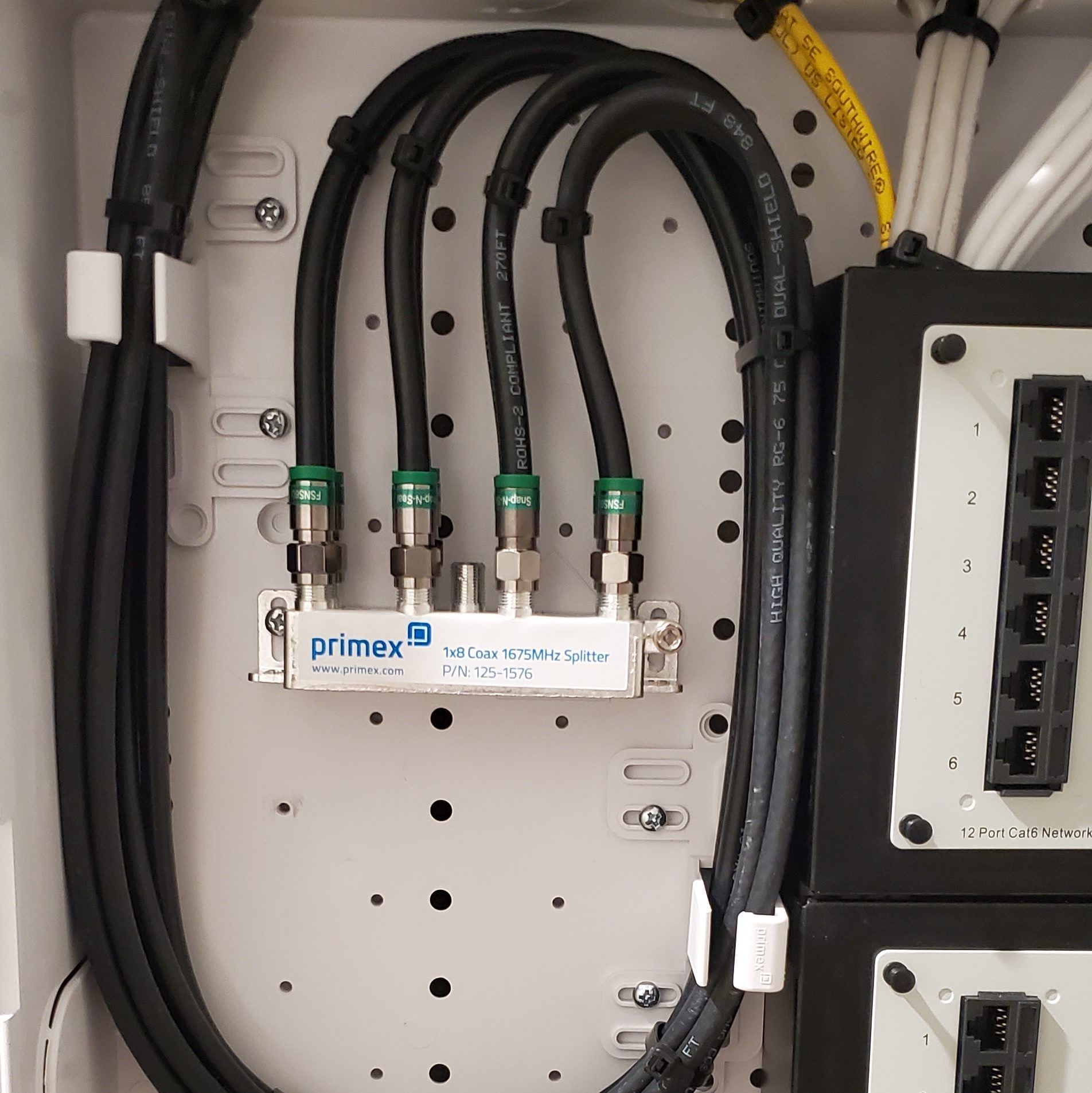 A white box with a cable splitter, four coaxial cables, and network ports.
