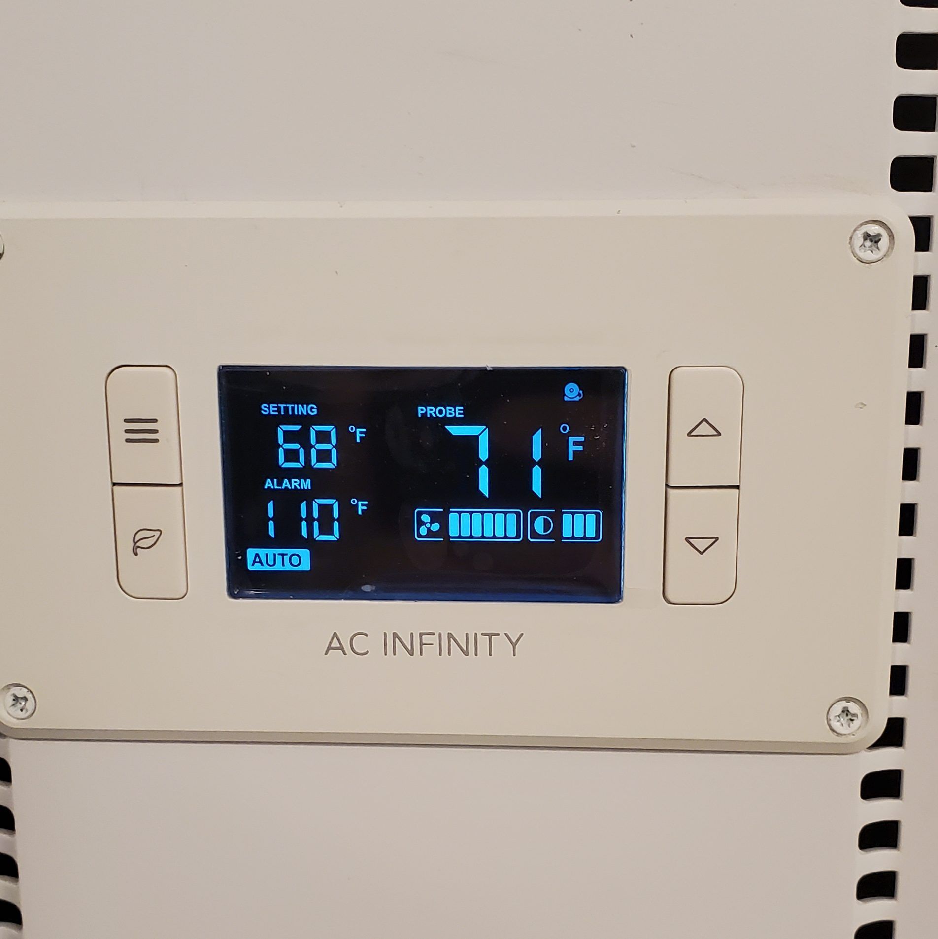 A digital thermostat with a blue display showing settings for temperature and fan speed.