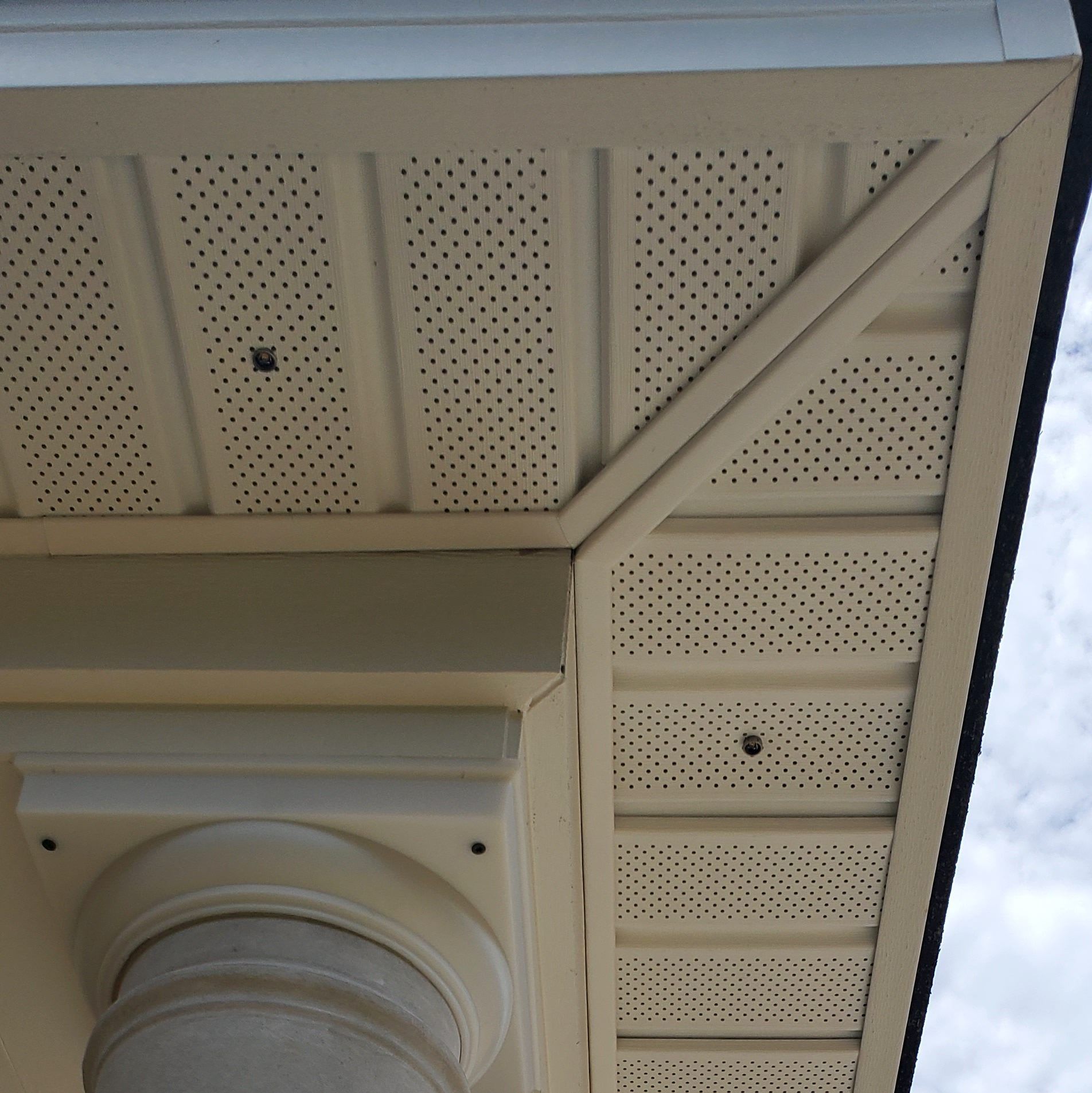 Beige soffit with perforated vent holes meets a column and a corner piece.
