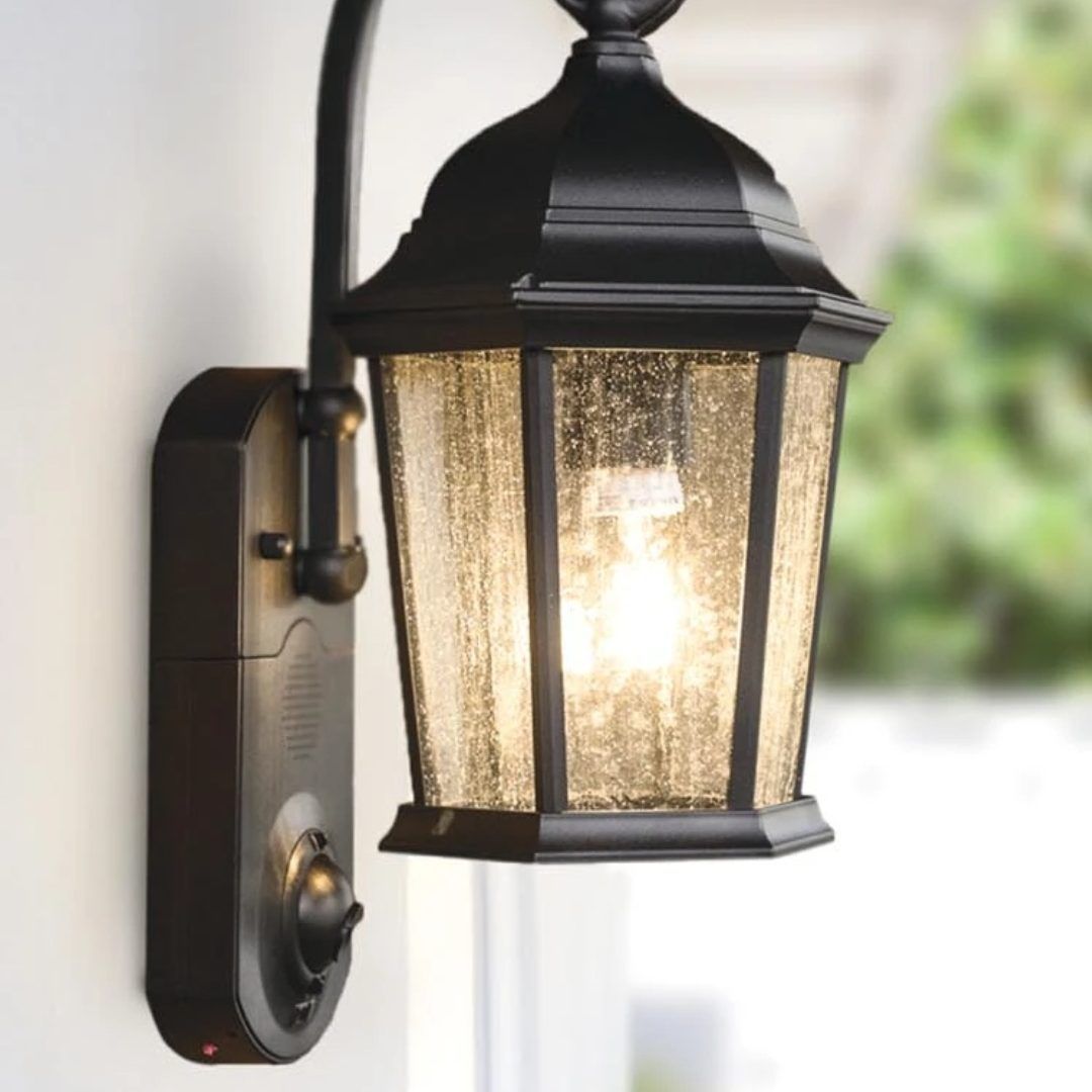 Black outdoor lantern with seeded glass panes, mounted on a wall next to a motion sensor.
